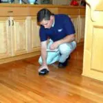 Power Dry KC employee inspecting a homeowner's hardwood floor to assist in their water damage insurance claim