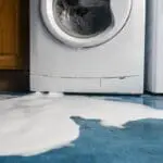 Soap bubbles pour out of a leaking washing machine.